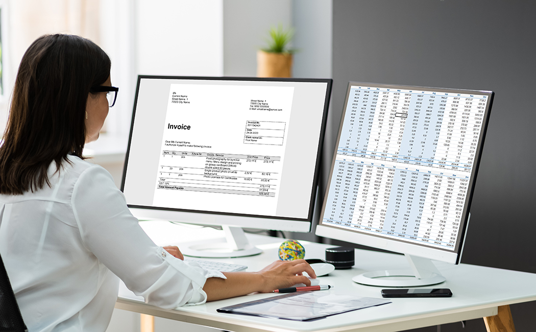 woman looking at finances on two monitors, Finance & Accounting | DXC Technology