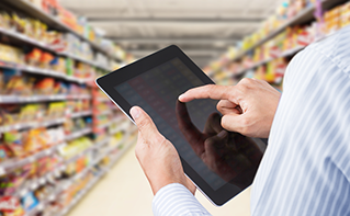 Manager using tablet in large supermarket aisle, grocery retailers must grow customer loyalty | DXC Technology Insights